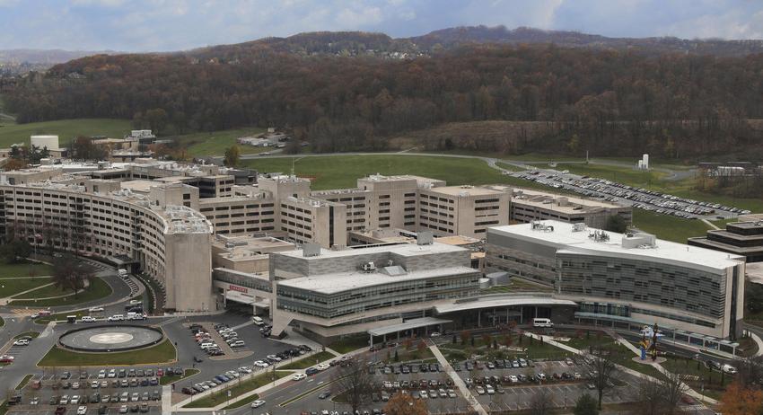 Aerial photo of a complex of buildings (Penn State 健康 Milton S. Hershey Medical Center) with mountains in the background.