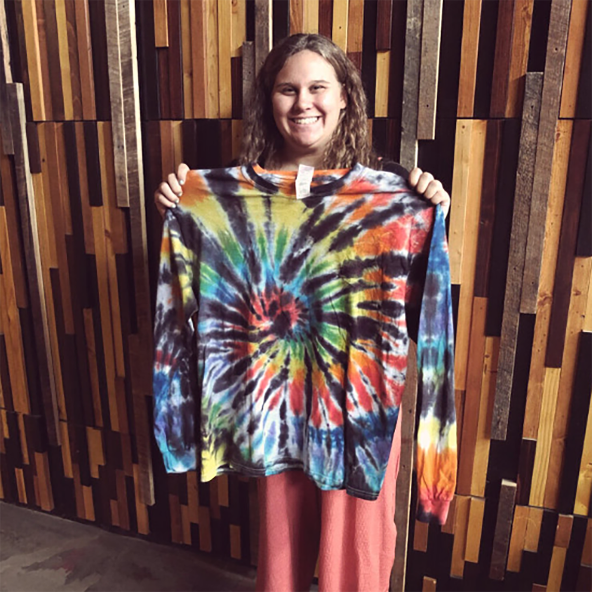 Photo of a young woman holding up a tie-dye shirt