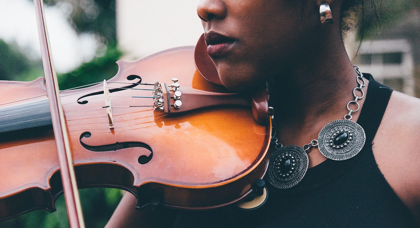 Close-up of a woman in formal clothing playing the violin.