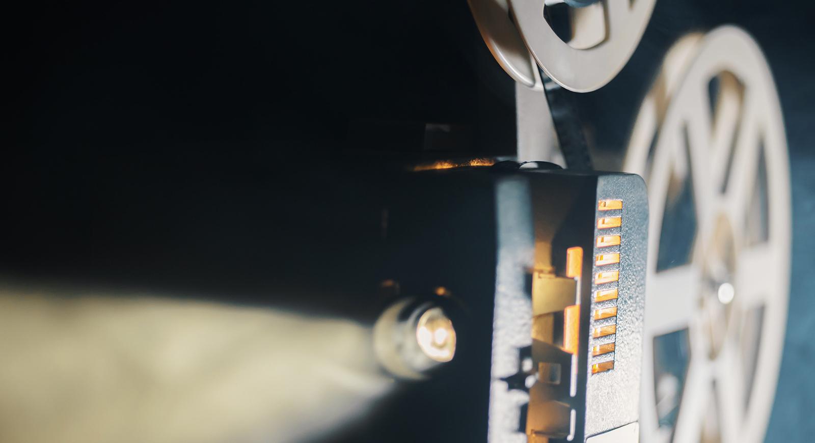 Close-up photo of an old fashioned projector streaming light through 电影 reels. 